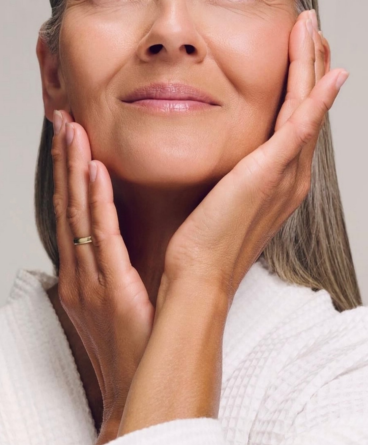Woman gently holding her face, serene expression.