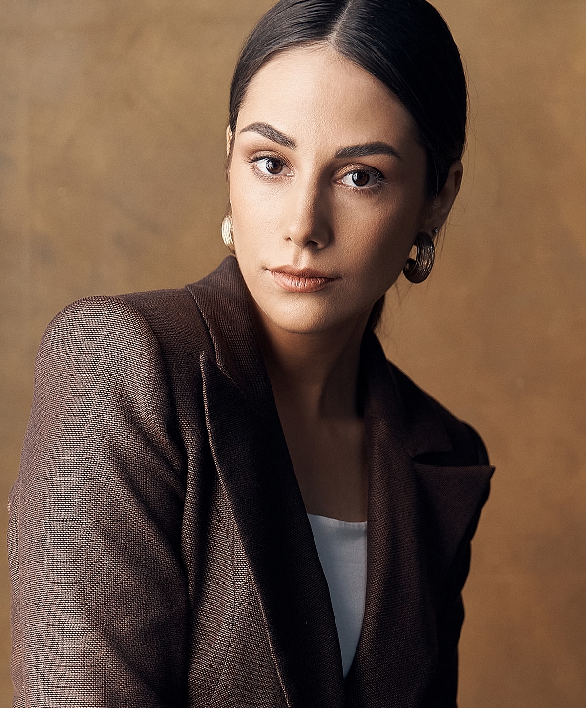 Woman in a dark blazer against a neutral background.