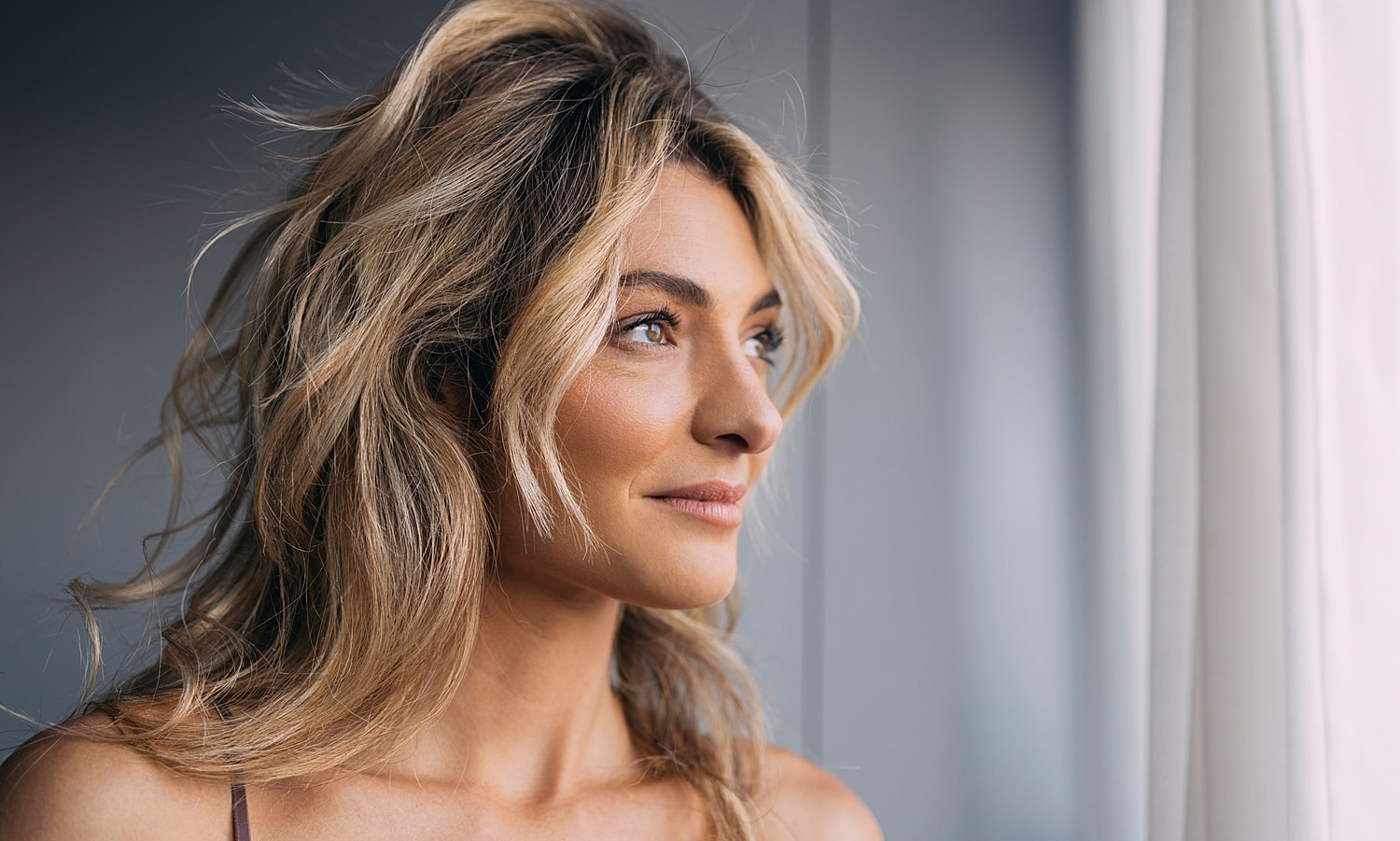 Woman gazing thoughtfully out of a window.