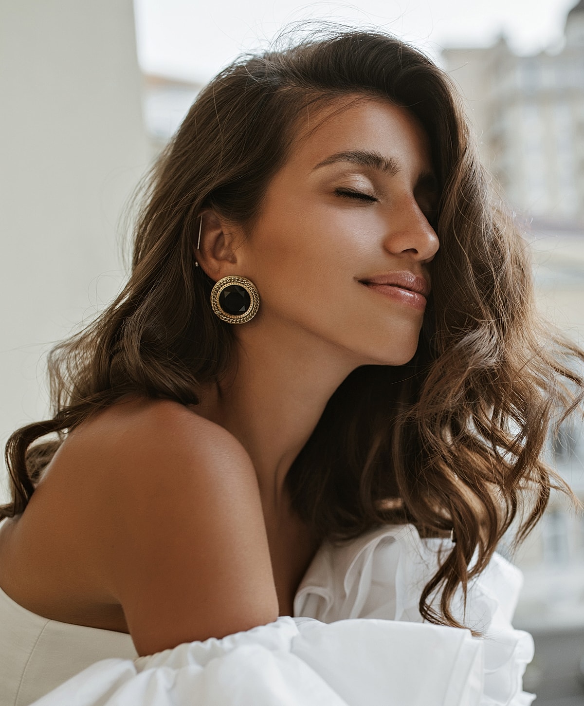 Woman with earrings and wavy brown hair.