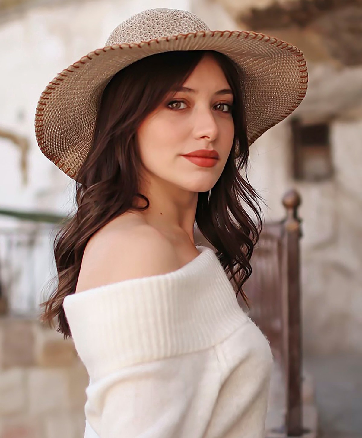 Woman in off-shoulder sweater and wide-brimmed hat.