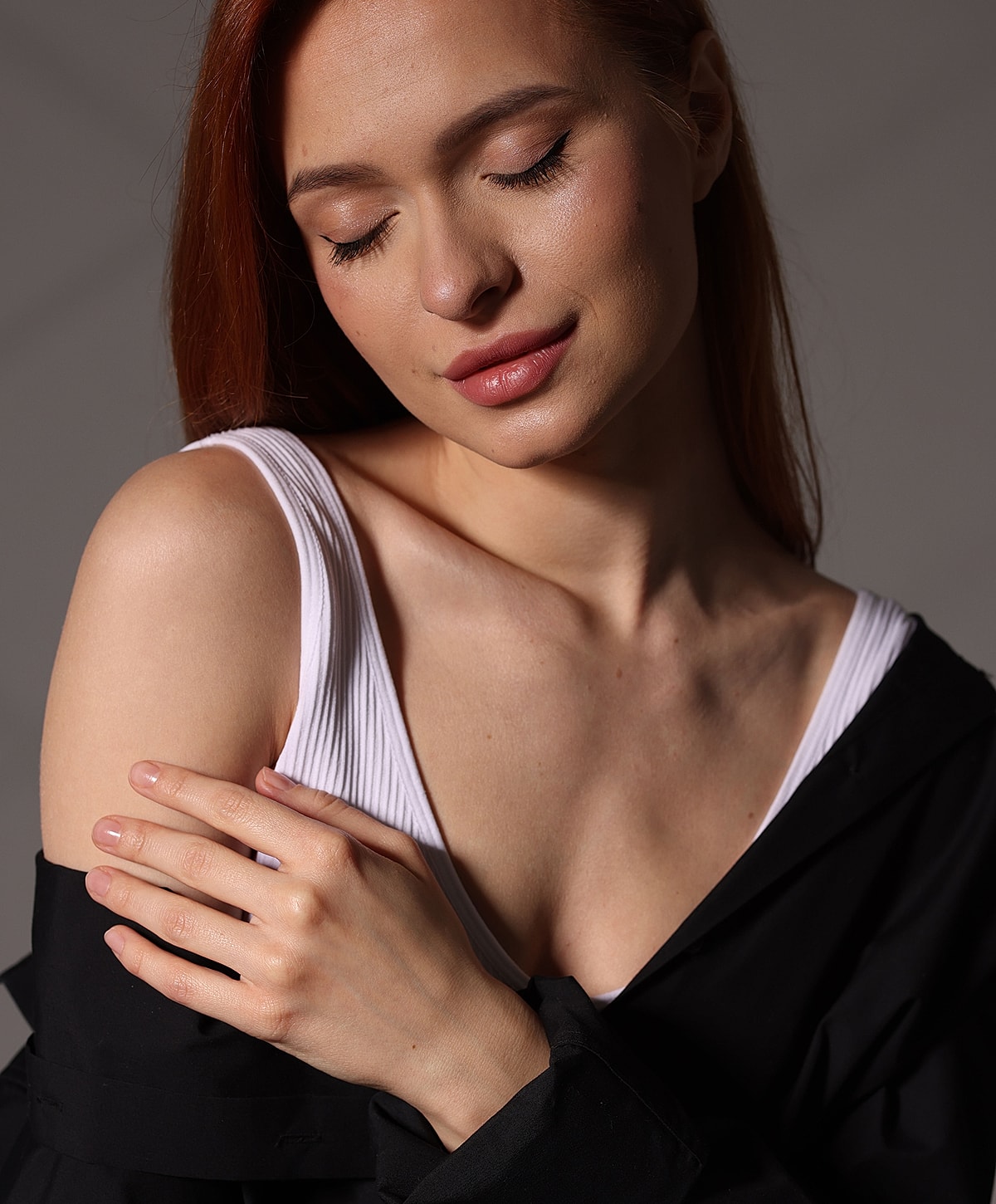 Woman with auburn hair, softly smiling, serene pose.