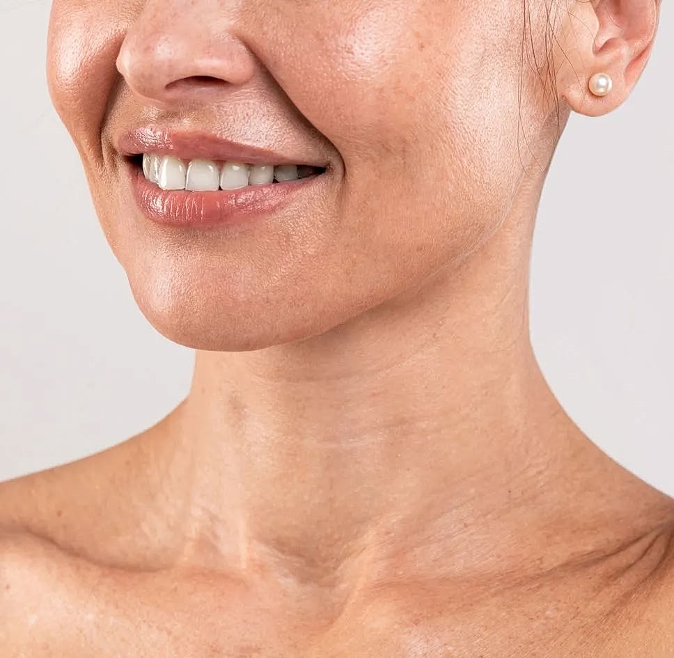 Smiling woman with pearl earrings and smooth skin.