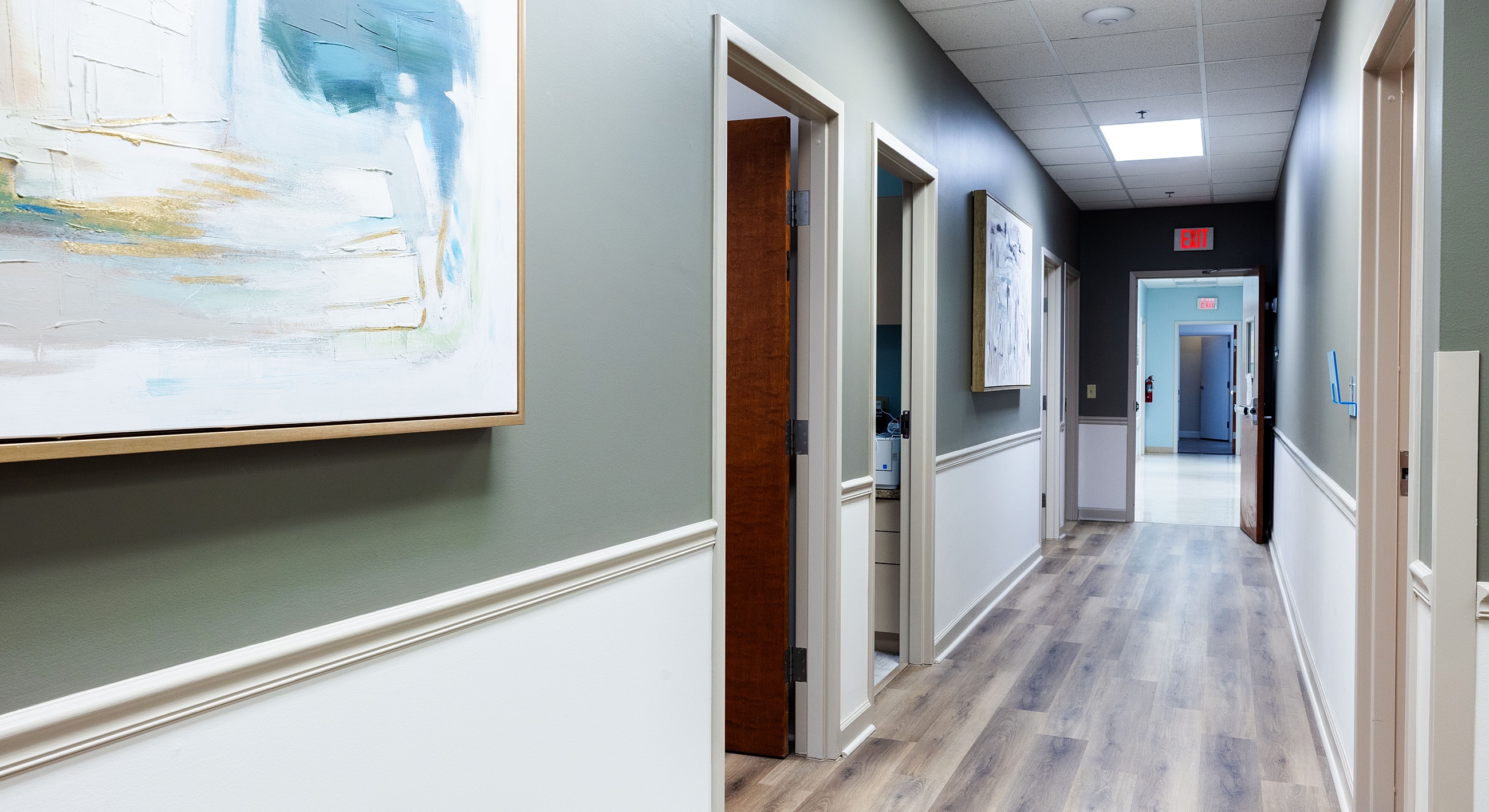 Modern office hallway with art and doors.