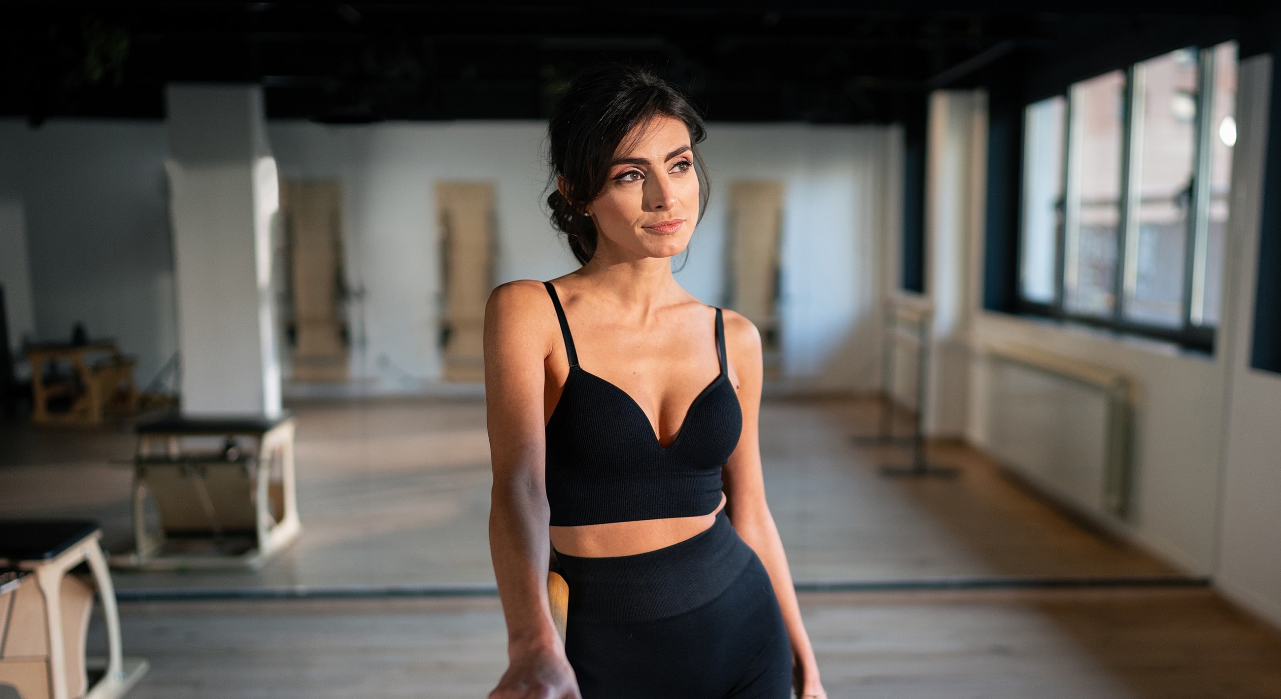 Woman posing in fitness studio with natural lighting.