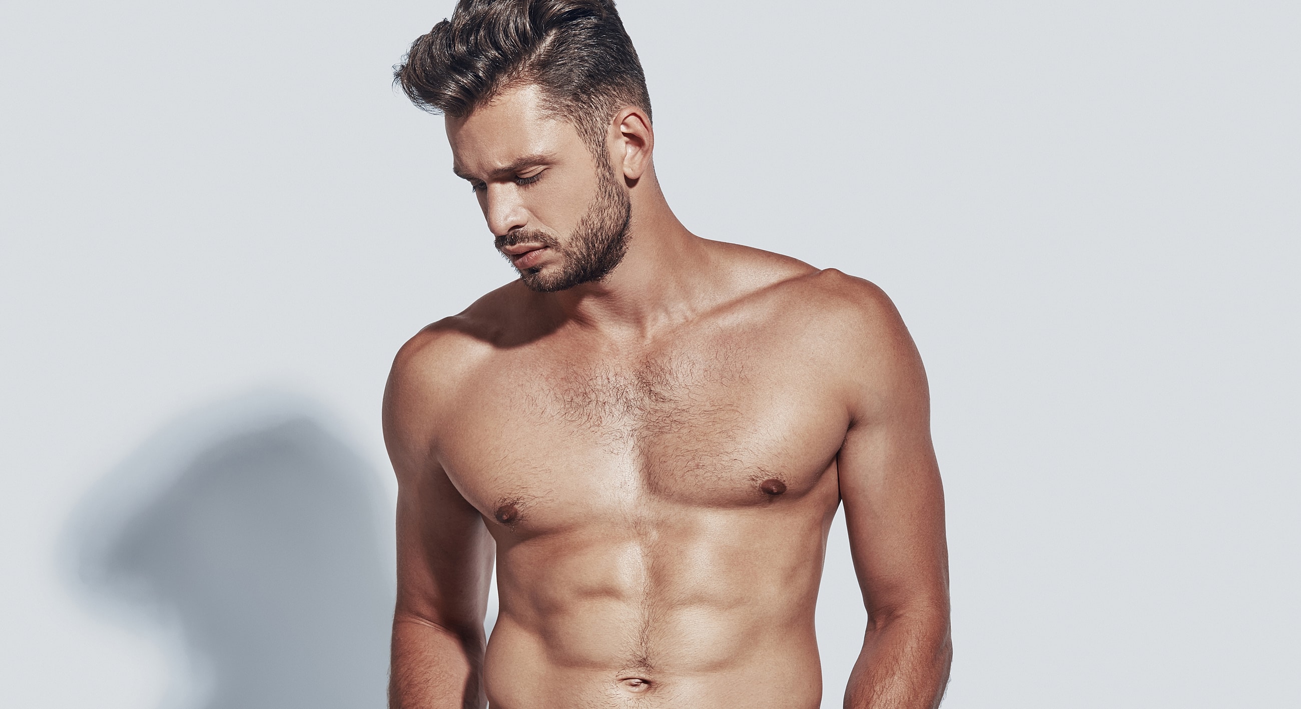 Shirtless man posing against a plain background