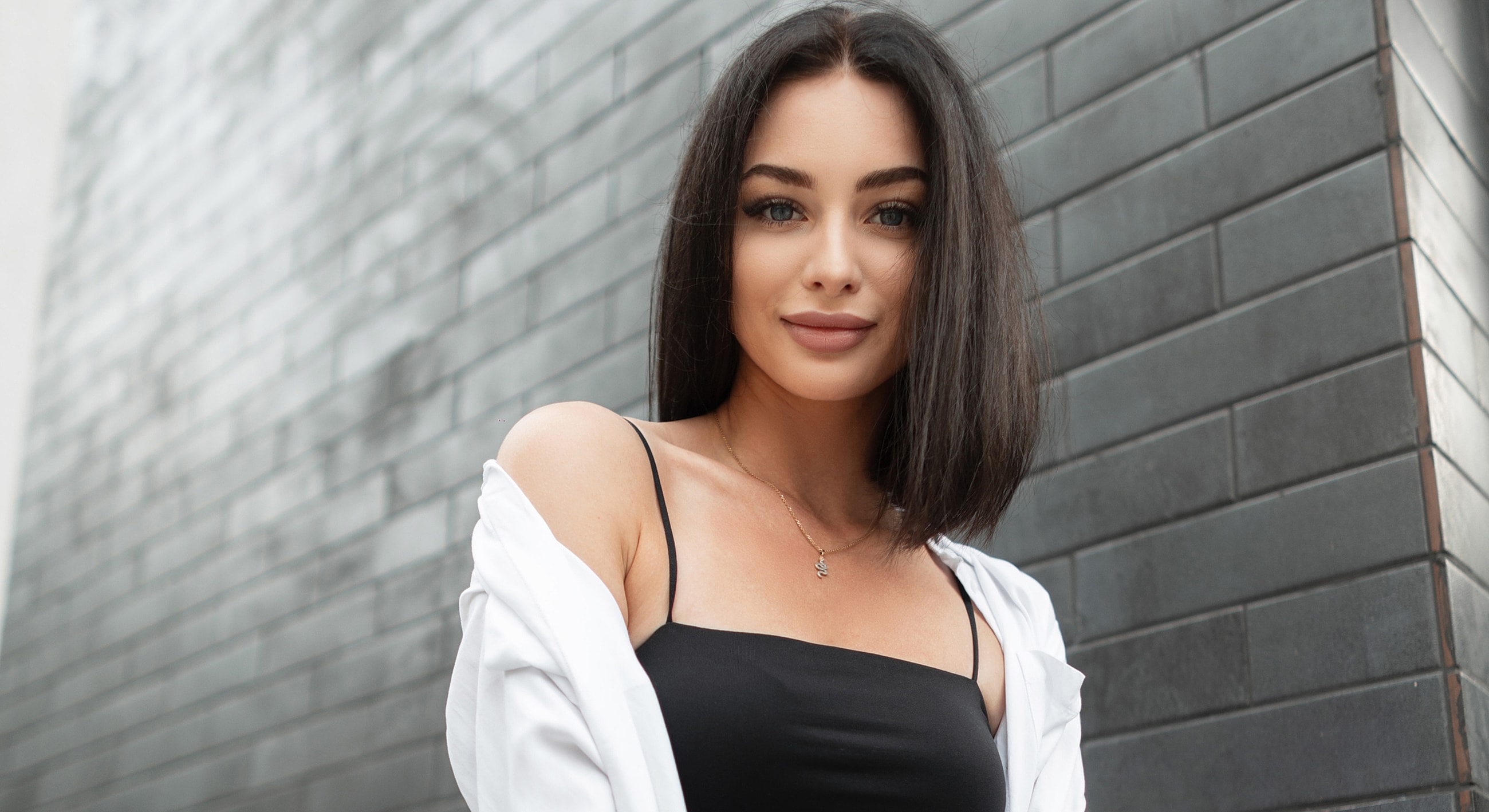 Woman in black top against textured wall.