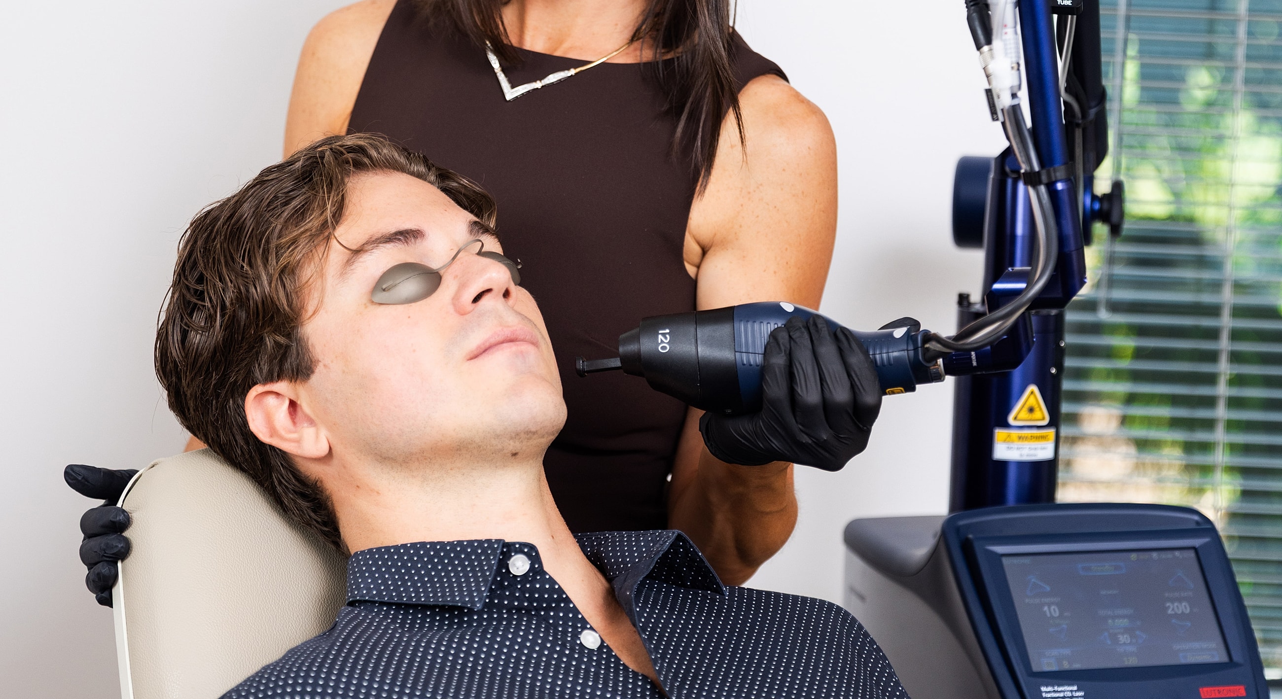 Man receiving a laser treatment from technician.