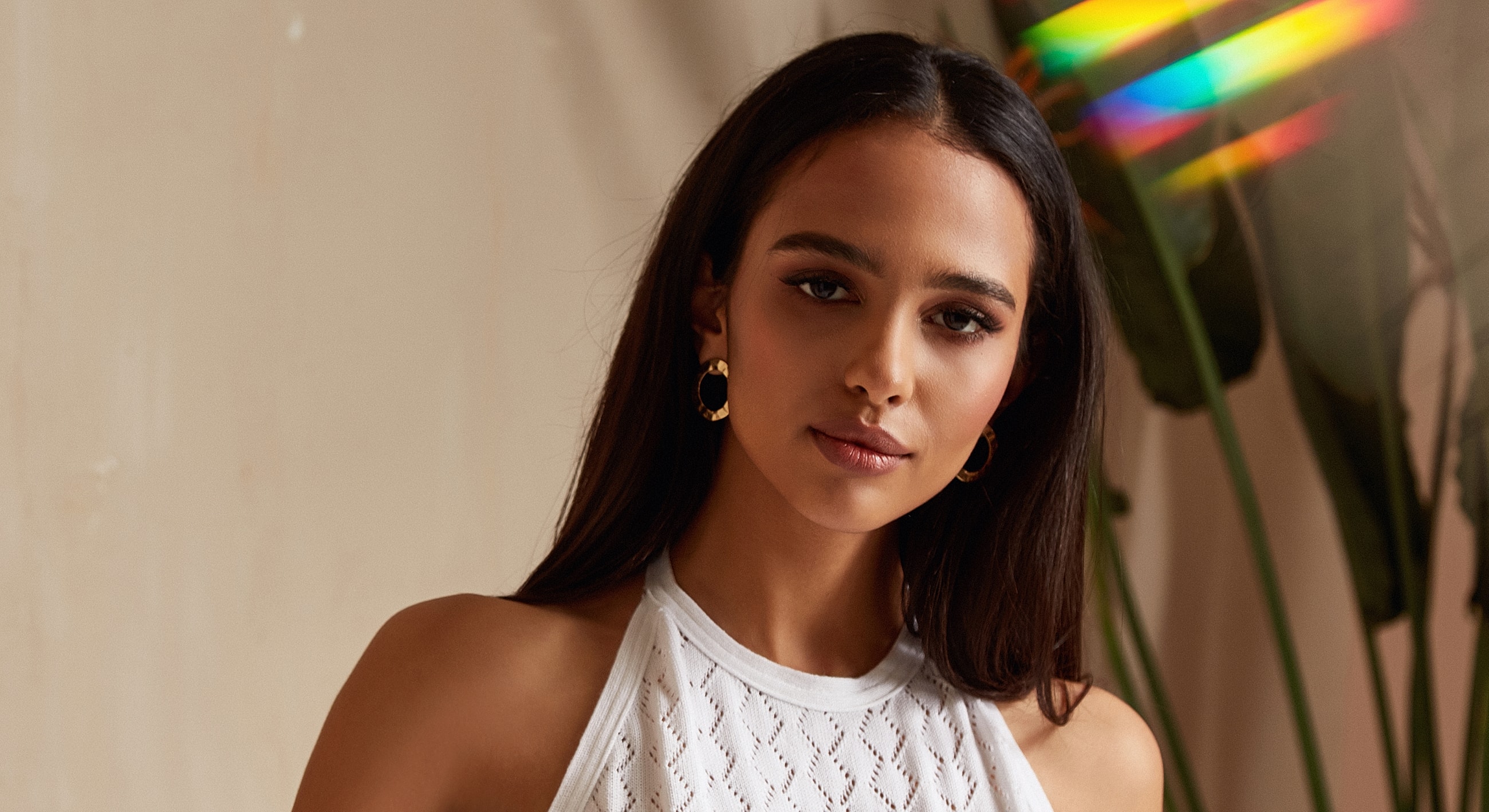 Smiling woman in white top with gold earrings.