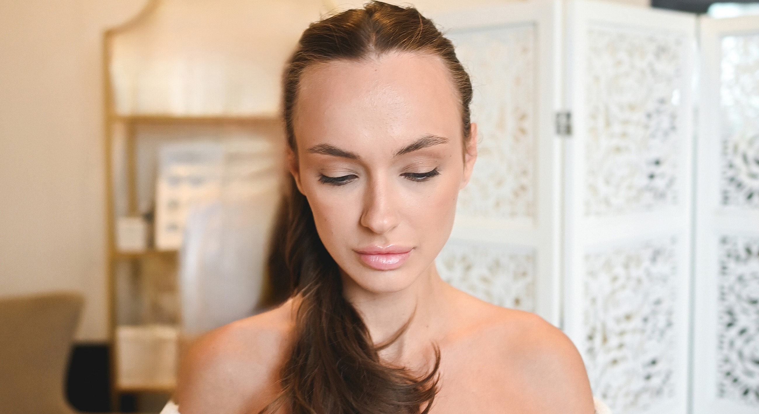 Woman with long hair looking downward indoors.